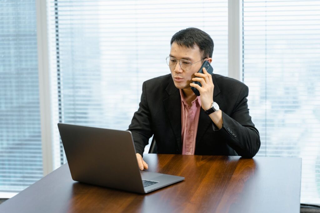 Conference-Event-Planning-Checklist_A-man-having-a-phonecall-while-using-his-laptop